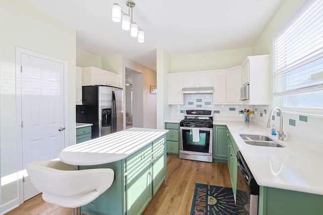 kitchen with hanging light fixtures, appliances with stainless steel finishes, sink, and green cabinetry