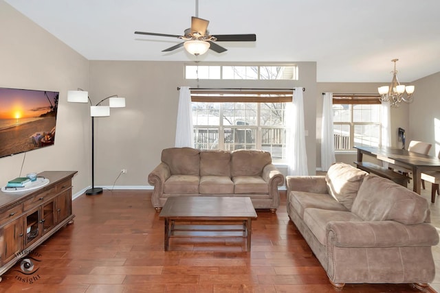 living room with ceiling fan with notable chandelier and dark hardwood / wood-style flooring