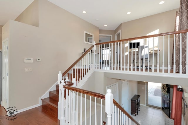 stairway featuring a towering ceiling and hardwood / wood-style flooring