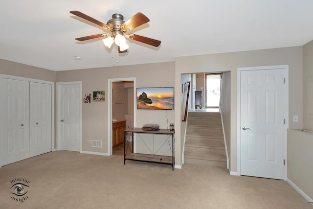 unfurnished bedroom featuring ceiling fan, light colored carpet, and ensuite bath