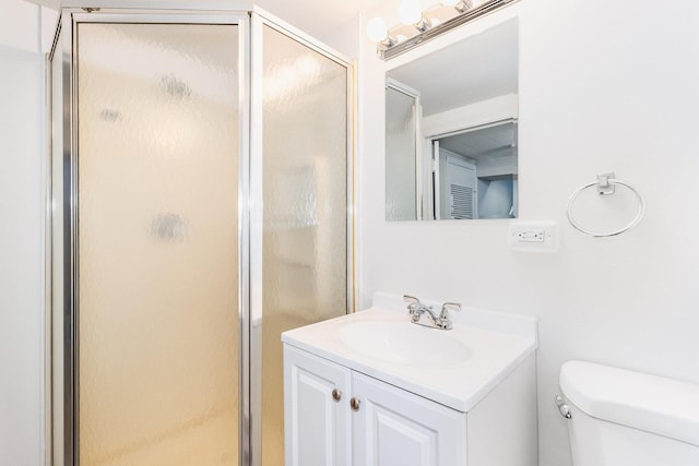 bathroom featuring a shower with door, vanity, and toilet