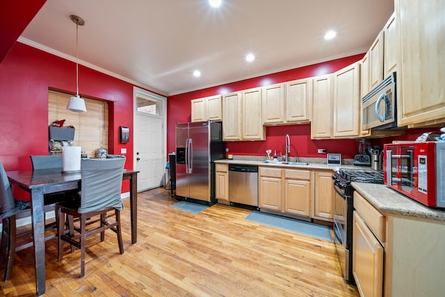 kitchen featuring pendant lighting, sink, stainless steel appliances, crown molding, and light wood-type flooring