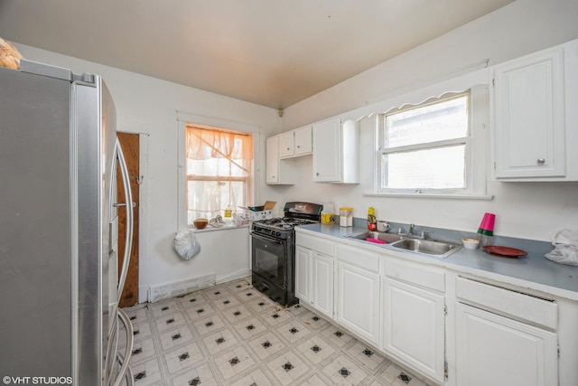 kitchen with white cabinetry, sink, stainless steel fridge, and gas stove