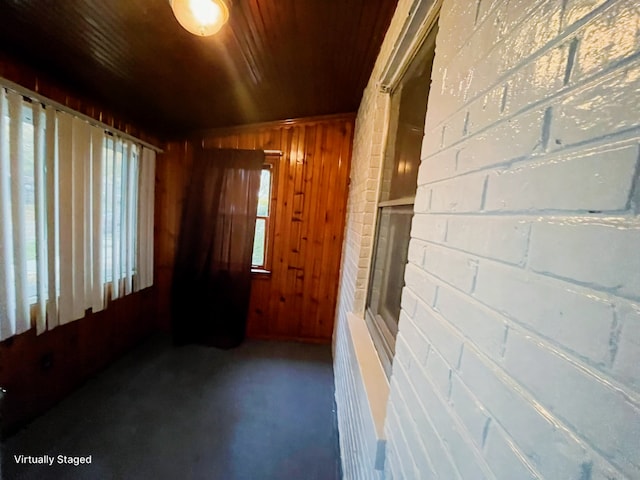 empty room with dark colored carpet, wood ceiling, and wood walls