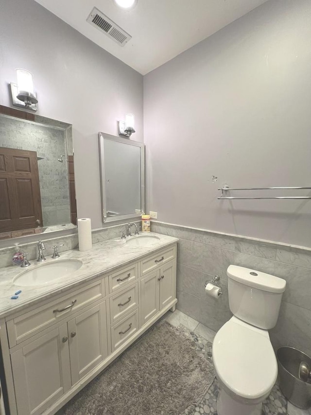 bathroom with vanity, tile patterned floors, toilet, and tile walls