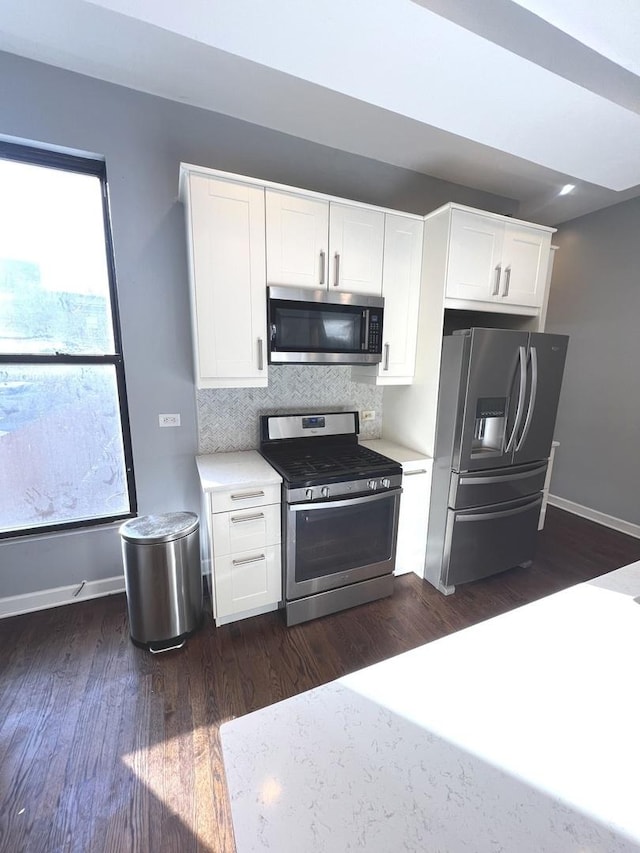 kitchen featuring stainless steel appliances, tasteful backsplash, dark wood-type flooring, and white cabinets