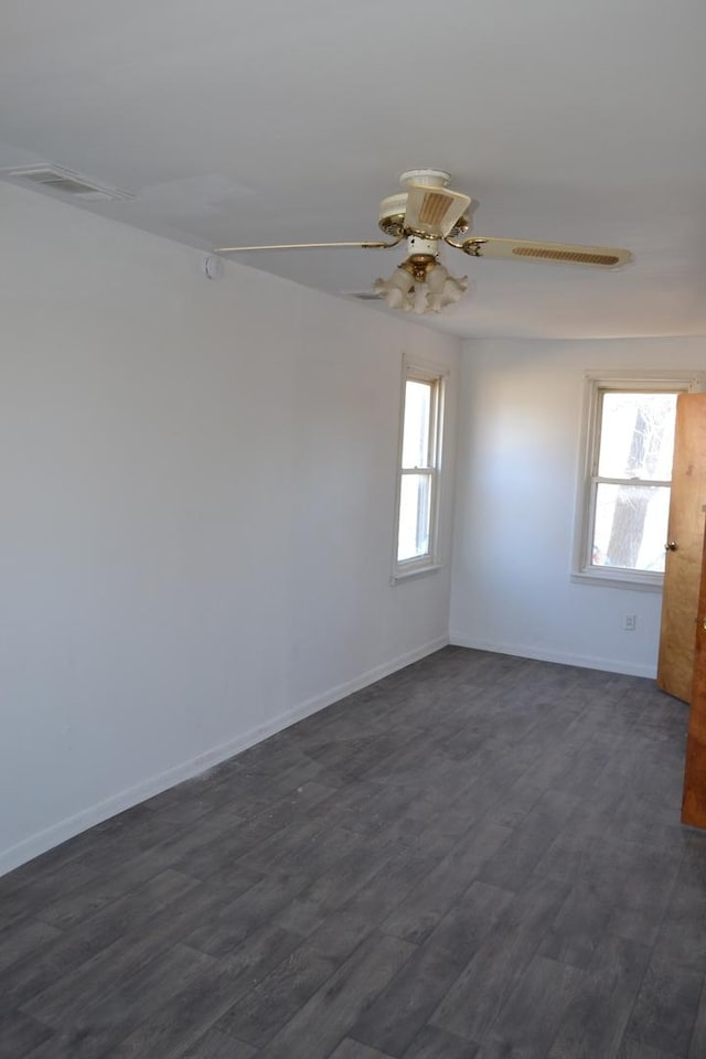 spare room featuring ceiling fan, a healthy amount of sunlight, and dark hardwood / wood-style flooring