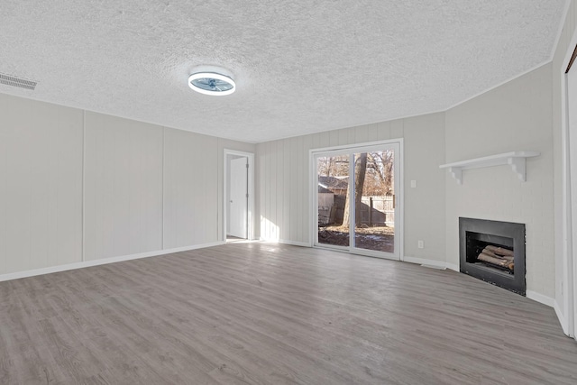 unfurnished living room with a textured ceiling and light hardwood / wood-style floors