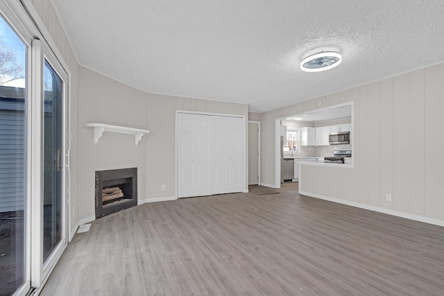 unfurnished living room featuring hardwood / wood-style flooring and a textured ceiling