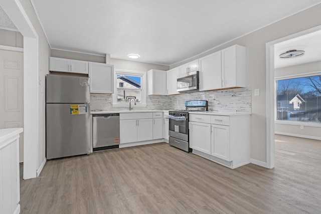 kitchen with white cabinetry, appliances with stainless steel finishes, sink, and light wood-type flooring