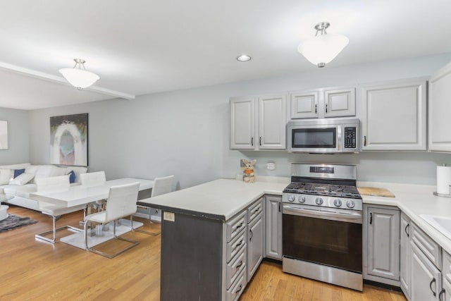 kitchen with light hardwood / wood-style flooring, gray cabinets, kitchen peninsula, and appliances with stainless steel finishes