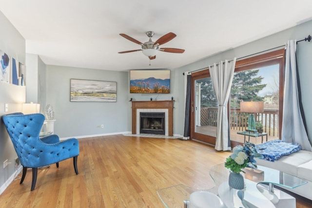 living area featuring light hardwood / wood-style flooring, a fireplace, and ceiling fan