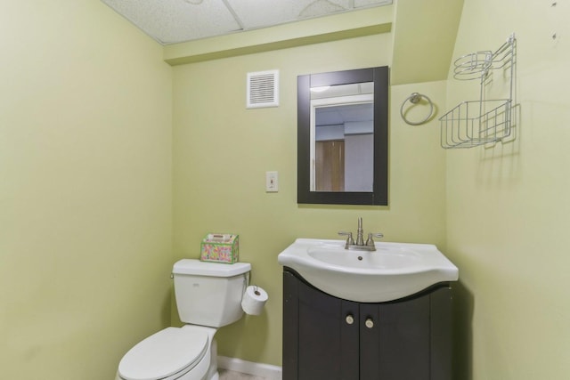 bathroom featuring vanity, toilet, and a drop ceiling