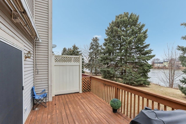 wooden terrace featuring a water view and a grill