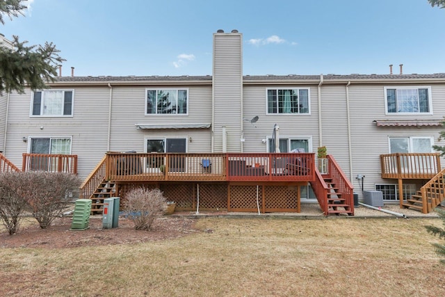 rear view of house featuring a wooden deck and a lawn