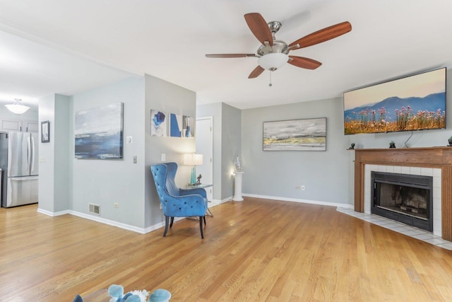 unfurnished room featuring a fireplace, ceiling fan, and light wood-type flooring