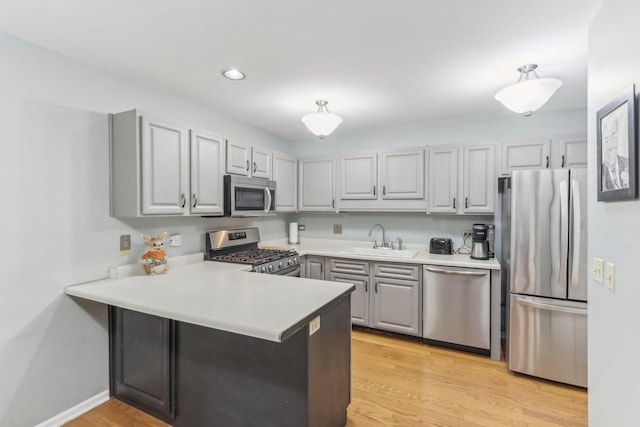 kitchen featuring sink, gray cabinets, kitchen peninsula, and appliances with stainless steel finishes