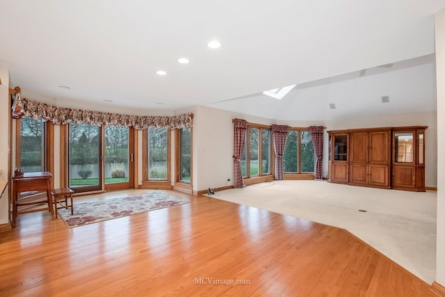 unfurnished living room featuring light hardwood / wood-style flooring, a wealth of natural light, and a skylight