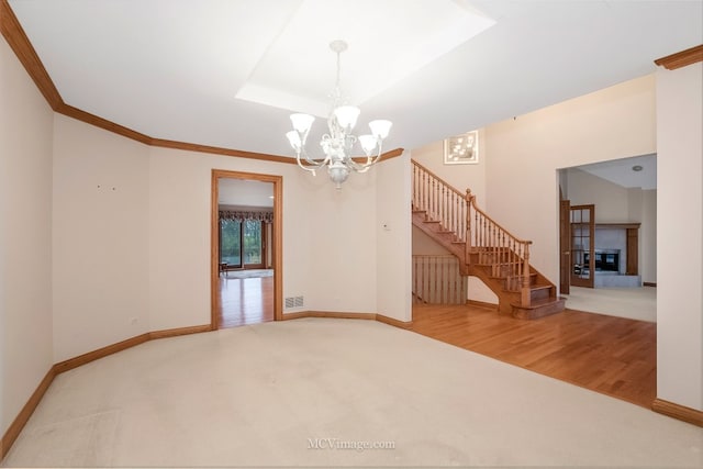 unfurnished room with an inviting chandelier, a tray ceiling, crown molding, and carpet flooring