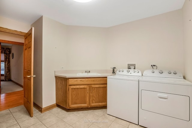 clothes washing area with light tile patterned flooring, cabinets, sink, and washer and dryer