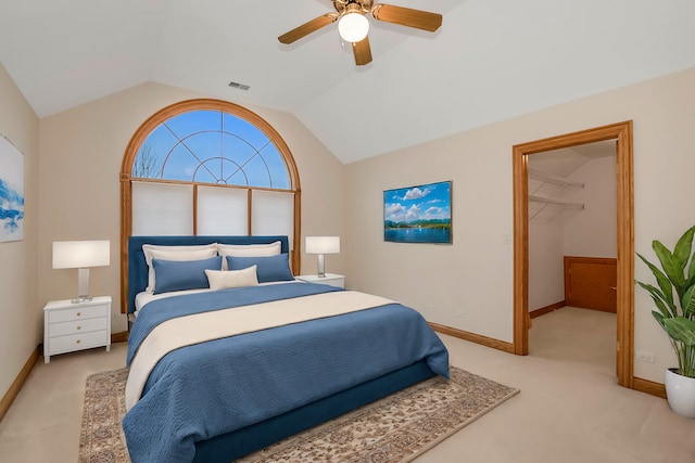 bedroom featuring lofted ceiling, a walk in closet, light colored carpet, and ceiling fan