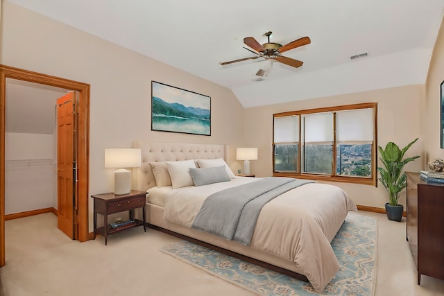 bedroom with ceiling fan, light colored carpet, lofted ceiling, and a spacious closet