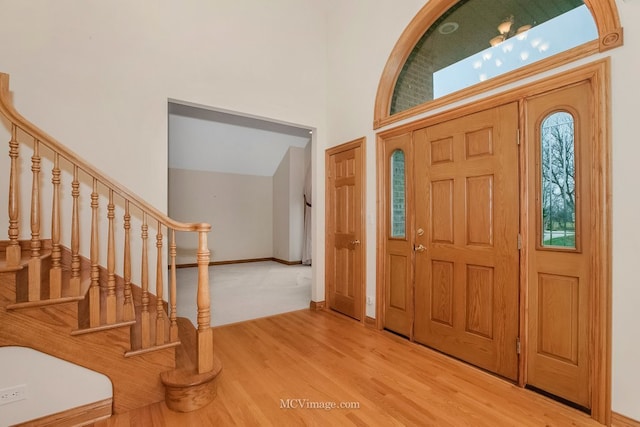 foyer entrance featuring hardwood / wood-style flooring and a towering ceiling