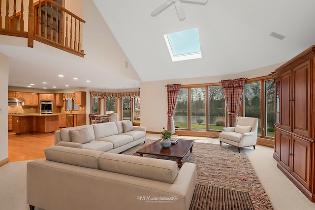 living room featuring ceiling fan, high vaulted ceiling, and a skylight