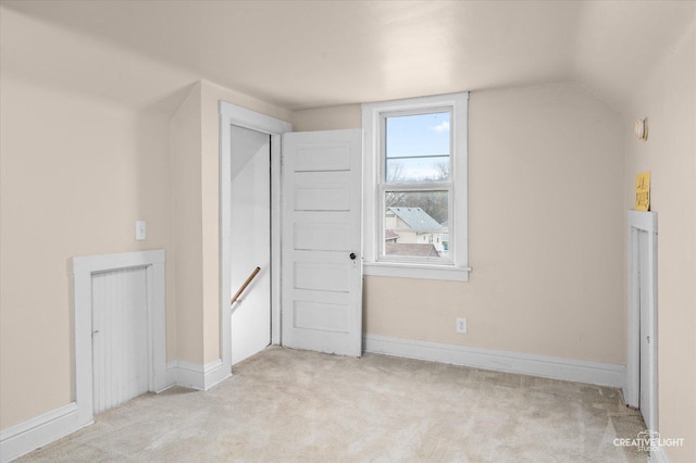 additional living space featuring vaulted ceiling and light colored carpet