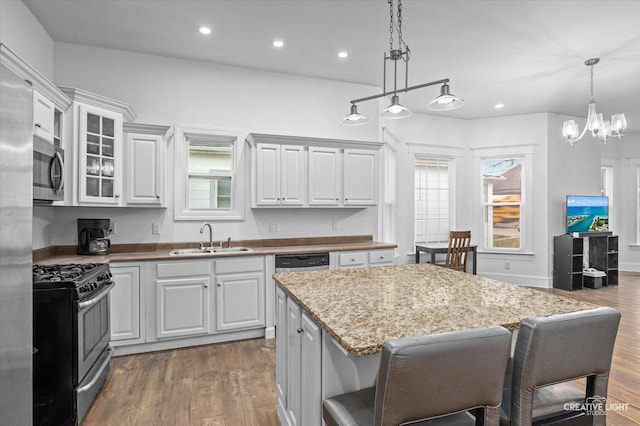 kitchen with stainless steel appliances, sink, white cabinets, and decorative light fixtures