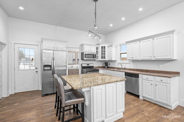 kitchen with a kitchen island, white cabinetry, appliances with stainless steel finishes, and hanging light fixtures