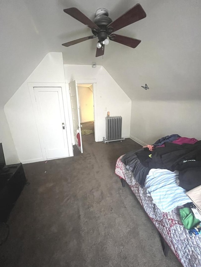 bedroom featuring dark colored carpet, lofted ceiling, radiator heating unit, and ceiling fan