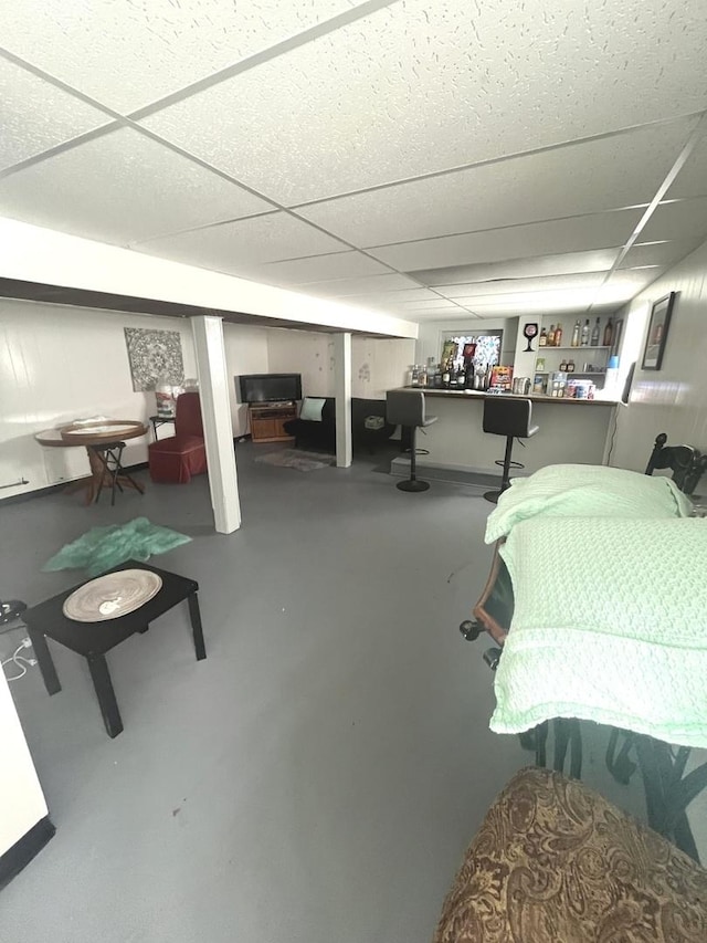 bedroom featuring concrete flooring and a drop ceiling