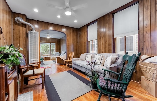 sitting room with wooden walls, ceiling fan, and light hardwood / wood-style flooring