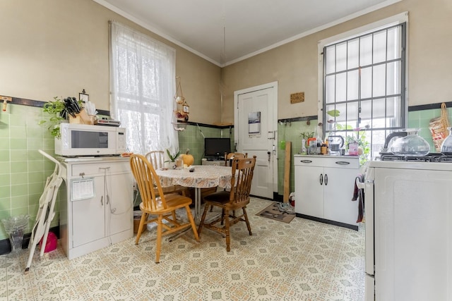 dining room featuring crown molding, washer / dryer, and tile walls