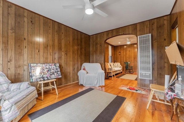 living room featuring hardwood / wood-style floors, ceiling fan, and wood walls