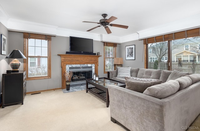 living room featuring light carpet, crown molding, a premium fireplace, and ceiling fan