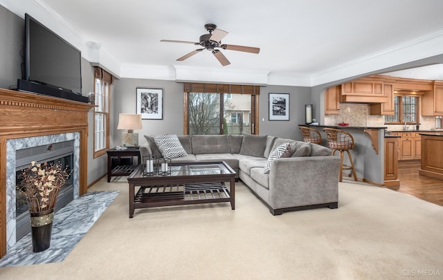 carpeted living room featuring crown molding, ceiling fan, and a fireplace