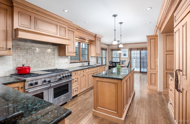 kitchen with sink, decorative light fixtures, light wood-type flooring, double oven range, and a kitchen island