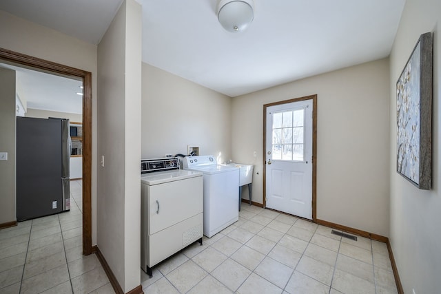 laundry area with washer and dryer and light tile patterned floors