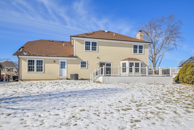 snow covered back of property with central AC unit and a deck