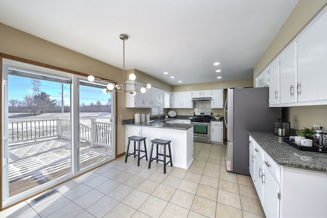 kitchen with light tile patterned flooring, decorative light fixtures, appliances with stainless steel finishes, kitchen peninsula, and white cabinets