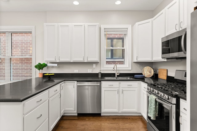 kitchen with appliances with stainless steel finishes, kitchen peninsula, sink, and white cabinets