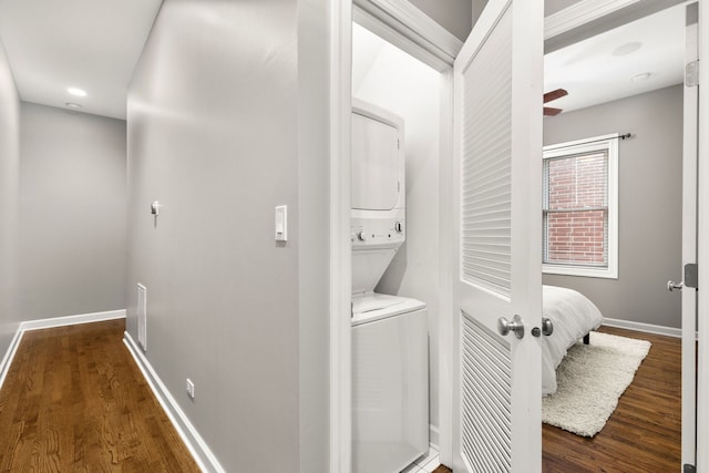 washroom featuring stacked washer and dryer and dark wood-type flooring