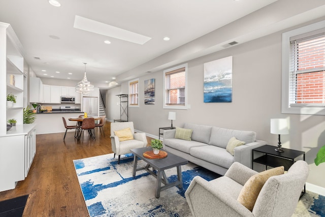 living room with dark hardwood / wood-style flooring and a skylight