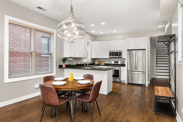 kitchen featuring sink, appliances with stainless steel finishes, white cabinetry, hanging light fixtures, and kitchen peninsula