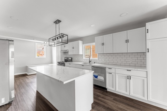 kitchen with a center island, hanging light fixtures, appliances with stainless steel finishes, dark hardwood / wood-style flooring, and white cabinets