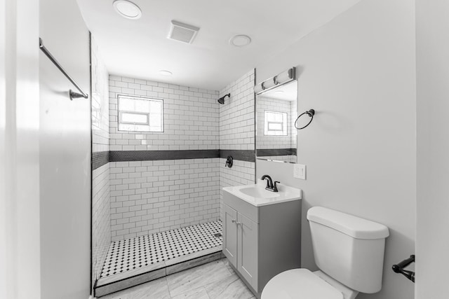 bathroom with vanity, toilet, and a tile shower