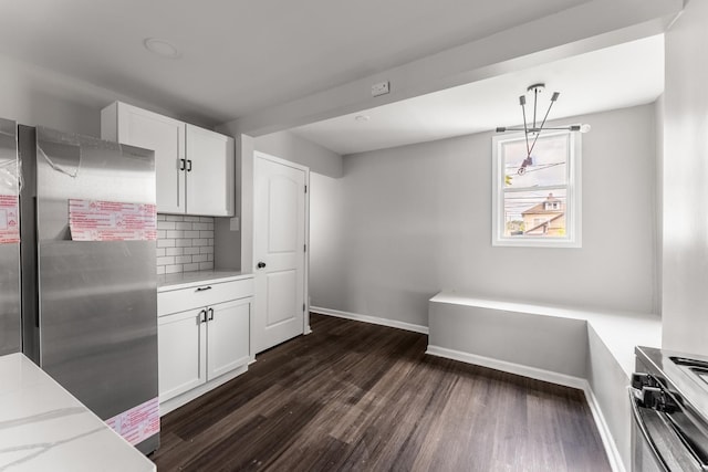 kitchen with white cabinetry, tasteful backsplash, stainless steel refrigerator, pendant lighting, and light stone countertops