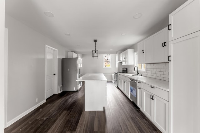 kitchen with sink, white cabinetry, a center island, hanging light fixtures, and stainless steel appliances